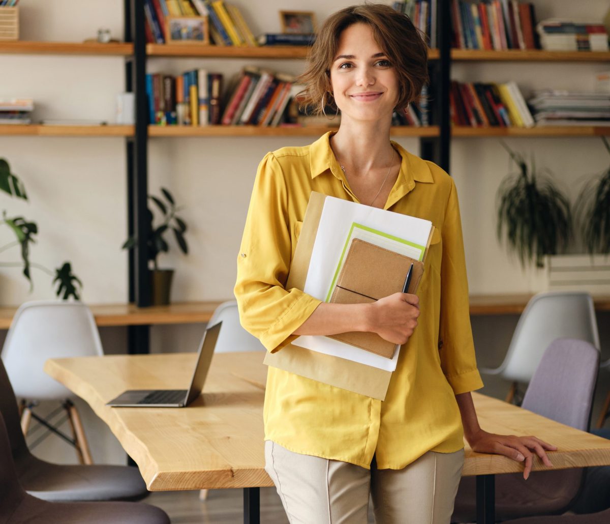 smiling-woman-in-yellow-shirt-with-notepad-and-pap-JKDM9YS-scaled.jpg